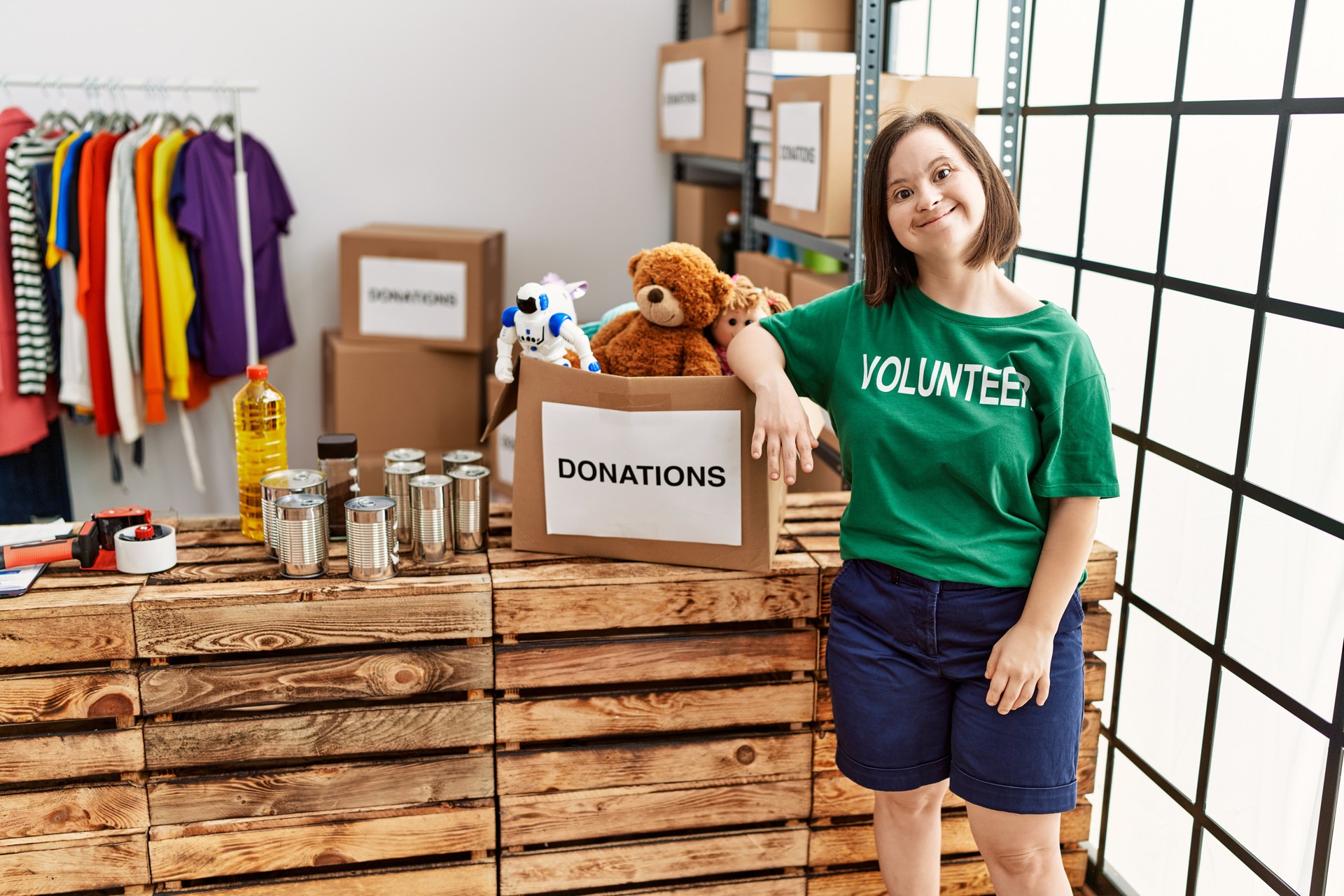 Brunette woman with down syndrome standing by box with donated toys at donations stand