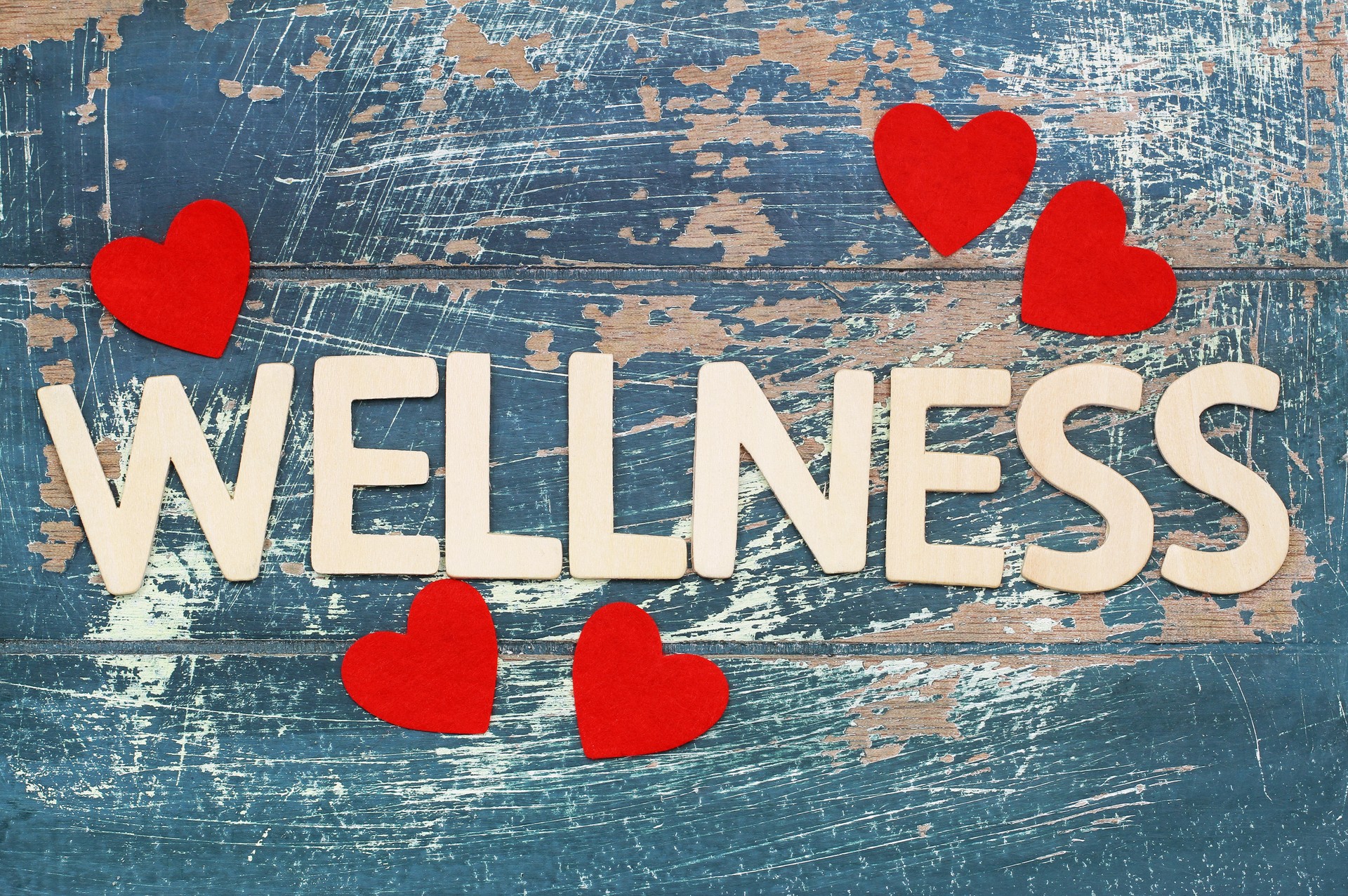 Wellness written with wooden letters on rustic surface with red hearts